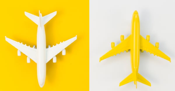 birds eye view of two toy airplanes on solid yellow and white backgrounds